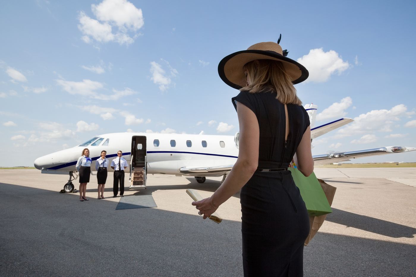 A woman walking toward a private jet and its crew