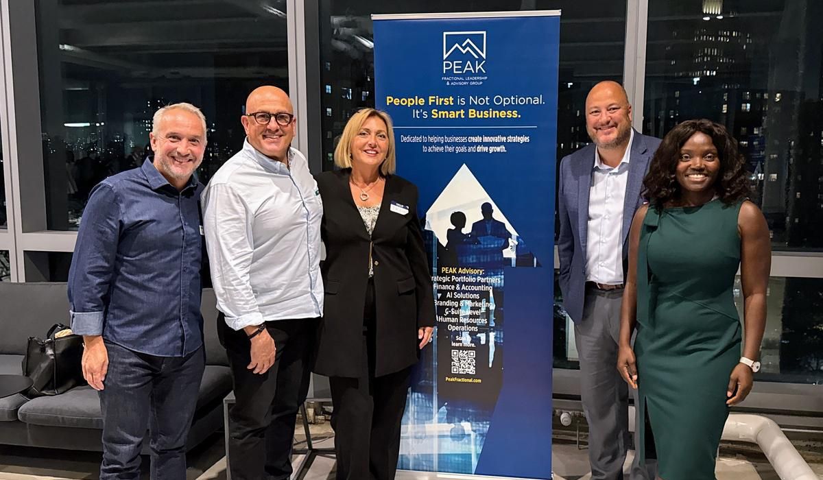 Peak team members with colleagues in front of the Peak banner in New York